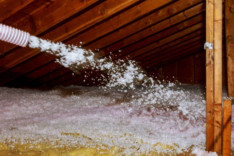 Combles d'une habitation avec charpente en bois apparente où s'effectue la projection d'isolant thermique par soufflage