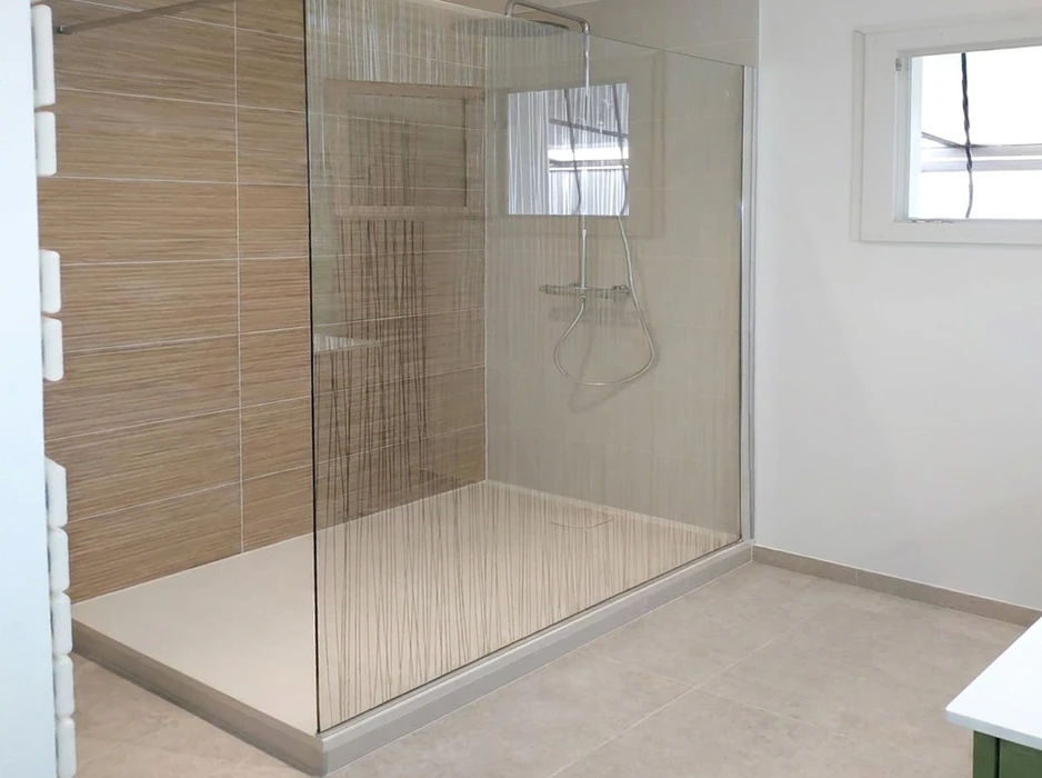 Salle de bain moderne avec baignoire îlot en pierre naturelle marbrée, sol en lattes de bois et galets décoratifs