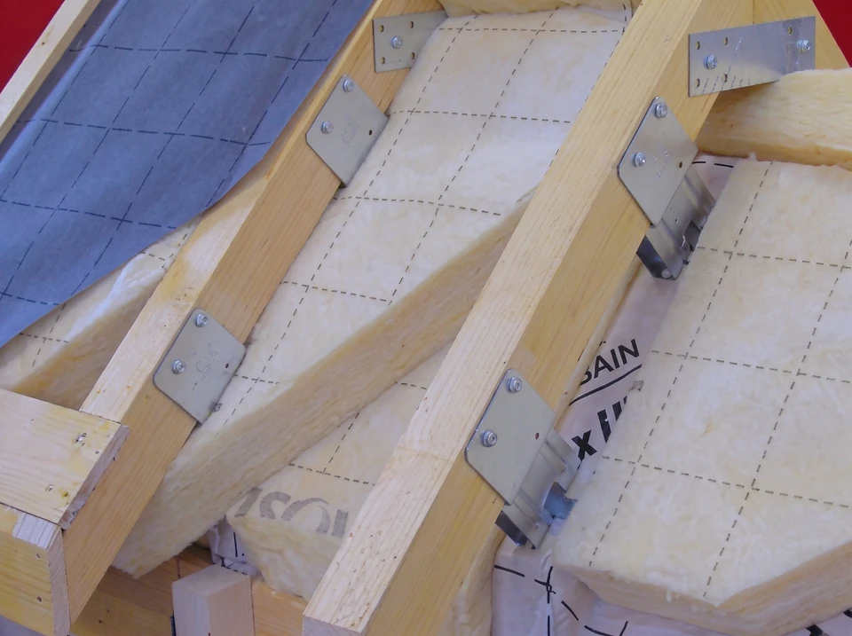 Combles en cours d'isolation thermique avec ossature bois apparente et fenêtre de toit installée